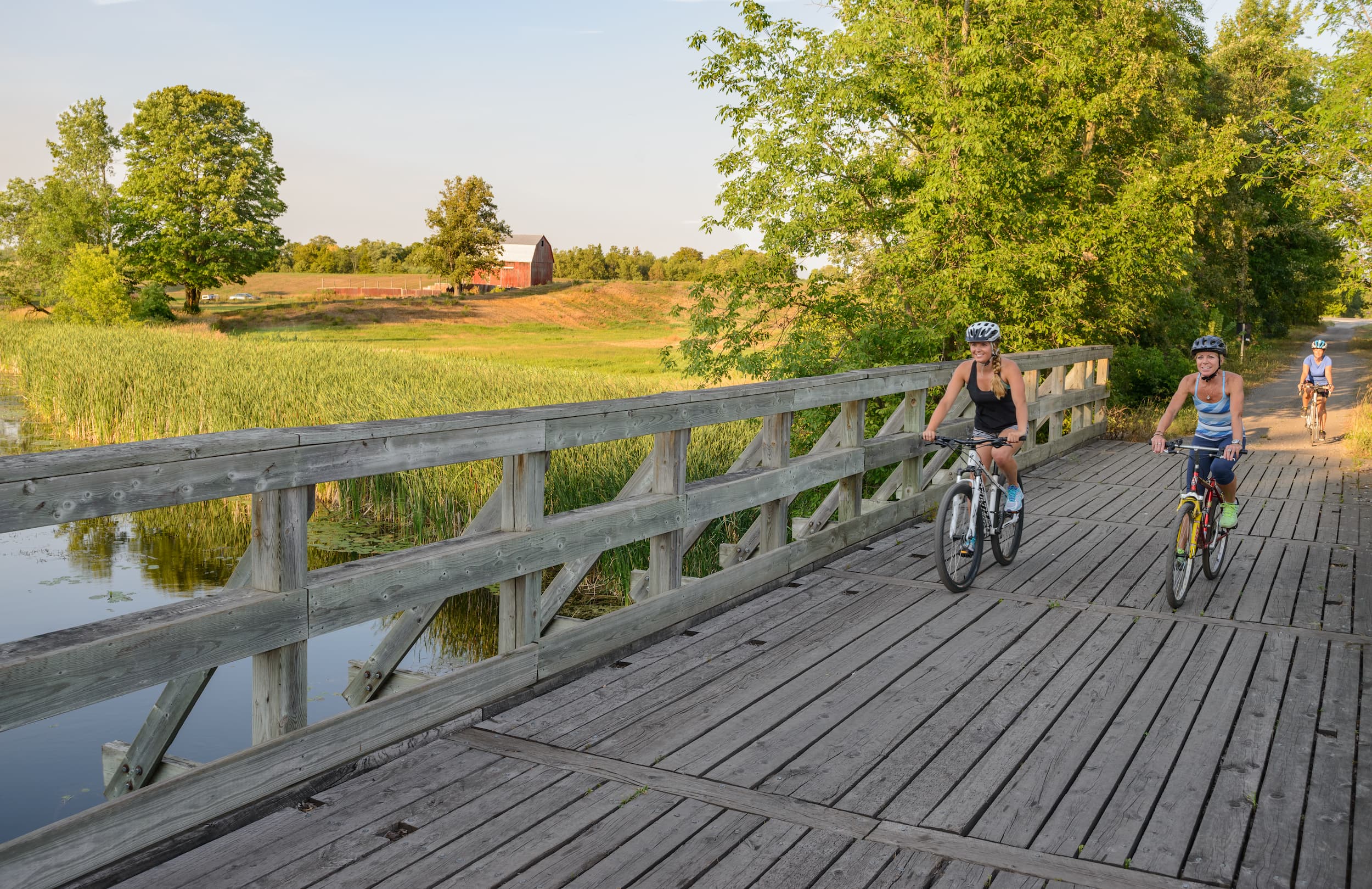 Two women riding bikes across a wooden bridge