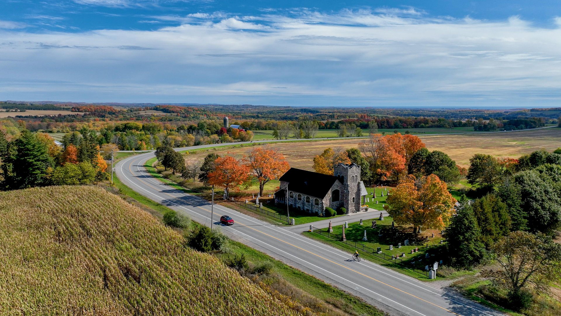 drone view of a car and cyclist on a country road in fall