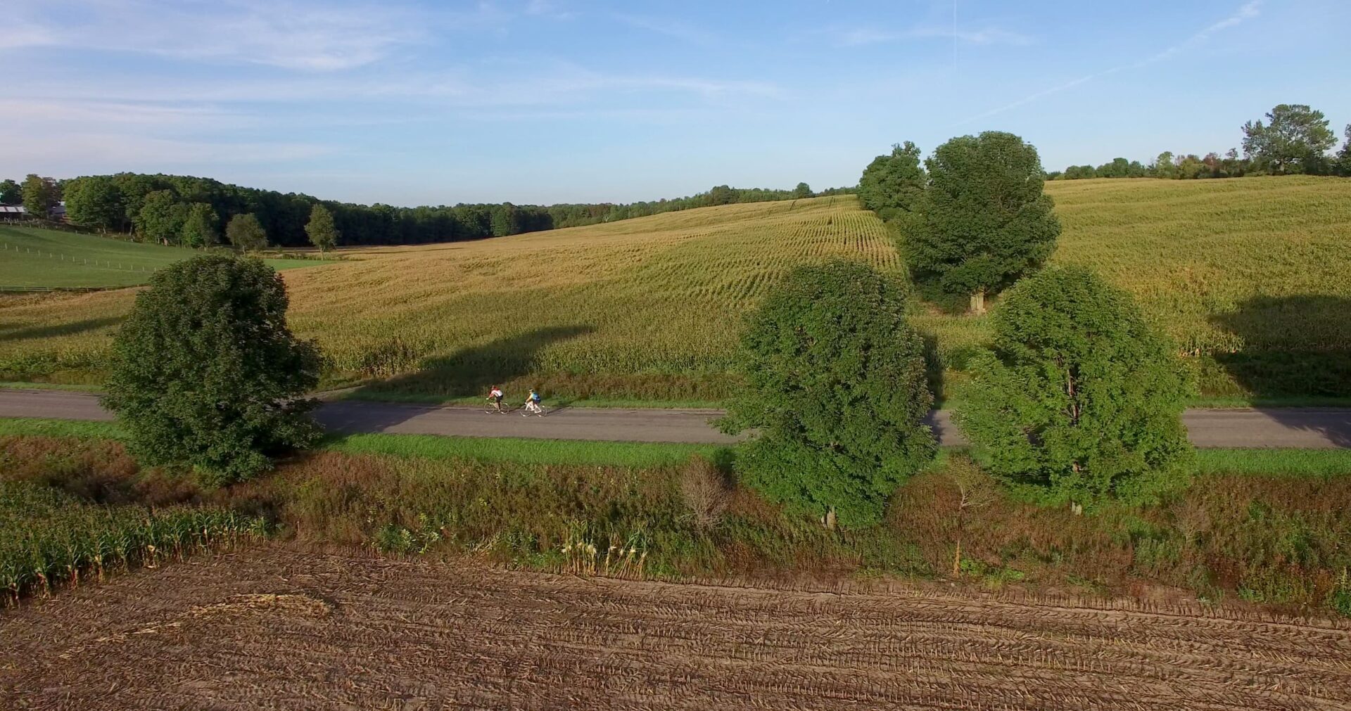 drone view of cyclists going past rolling hills