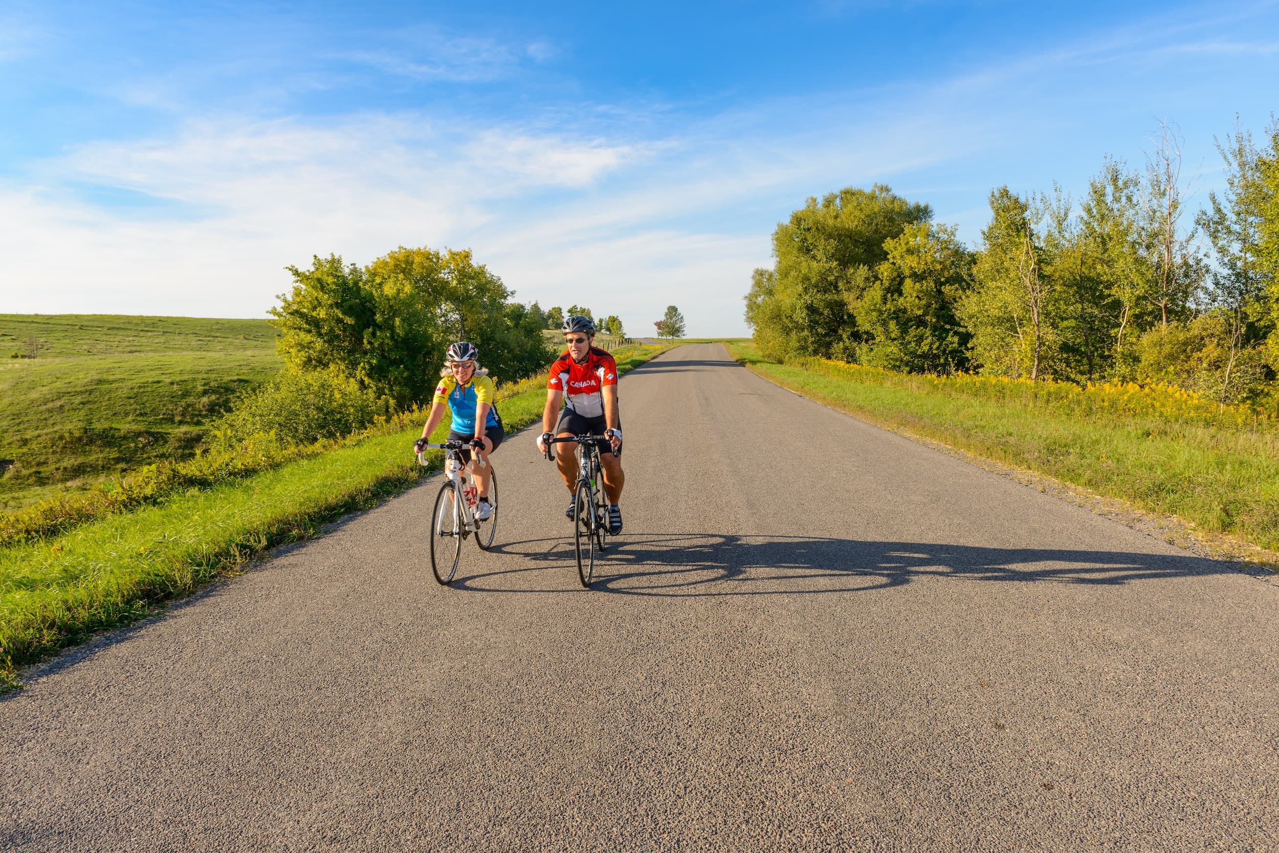 Man and woman riding bikes on a country road.
