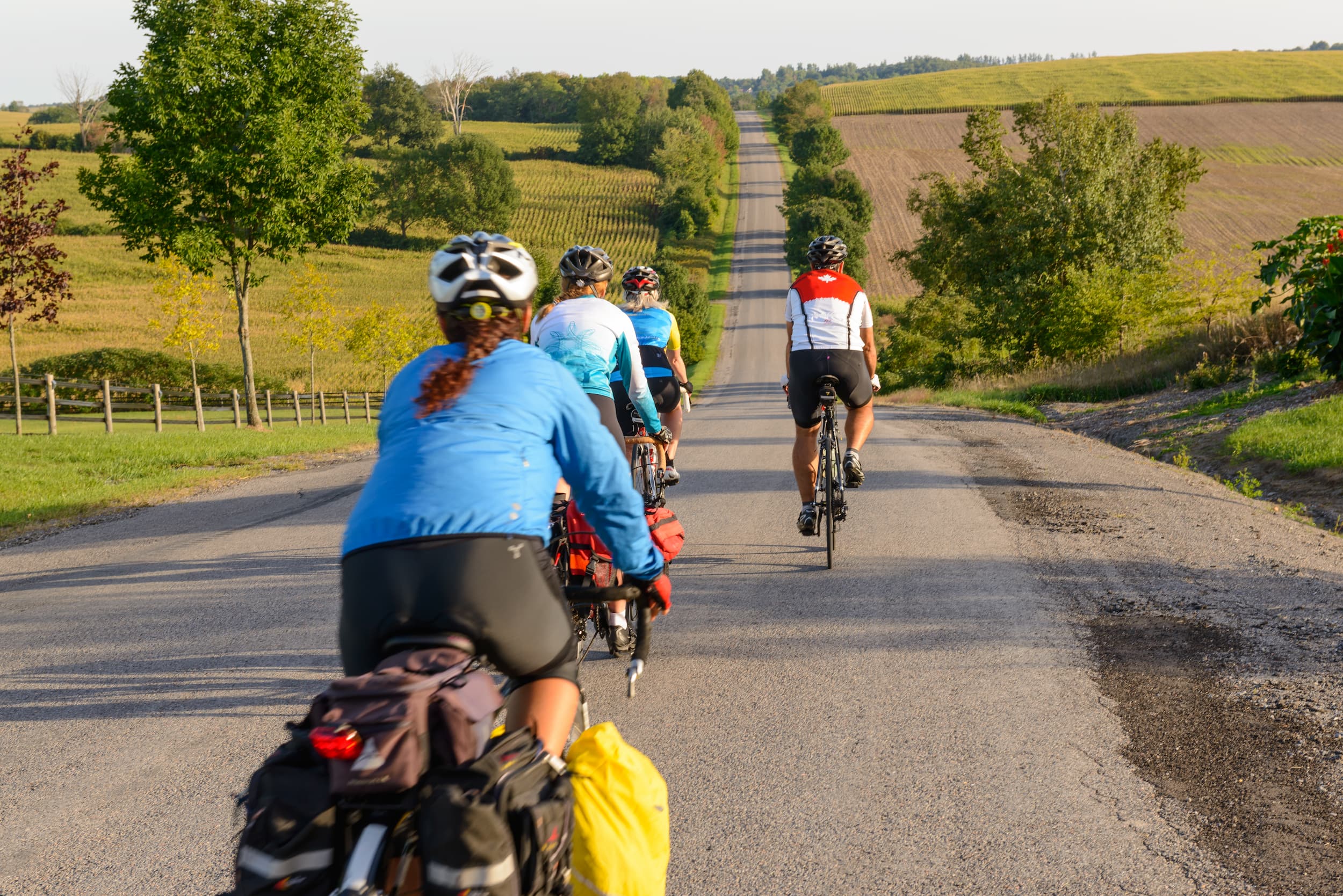 Group of people on bikes riding on a country road.