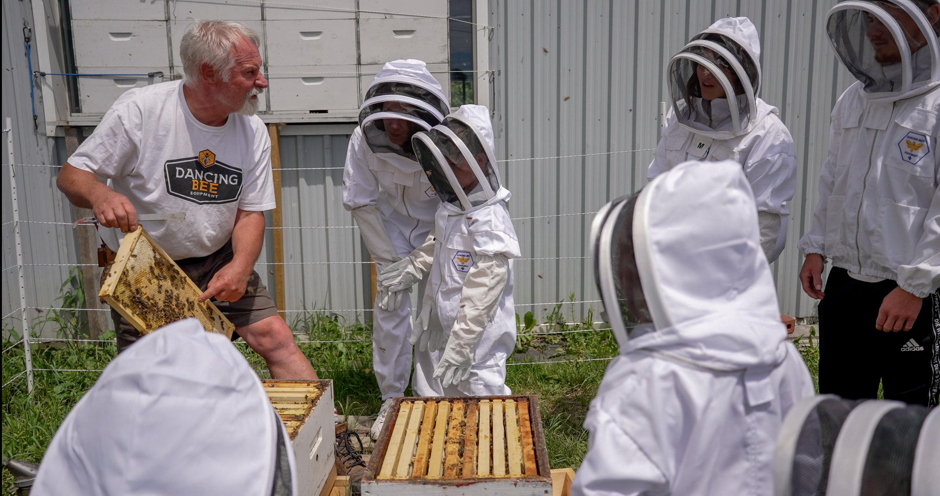 Group of people wearing beekeeper protective gear at a workshop about bees