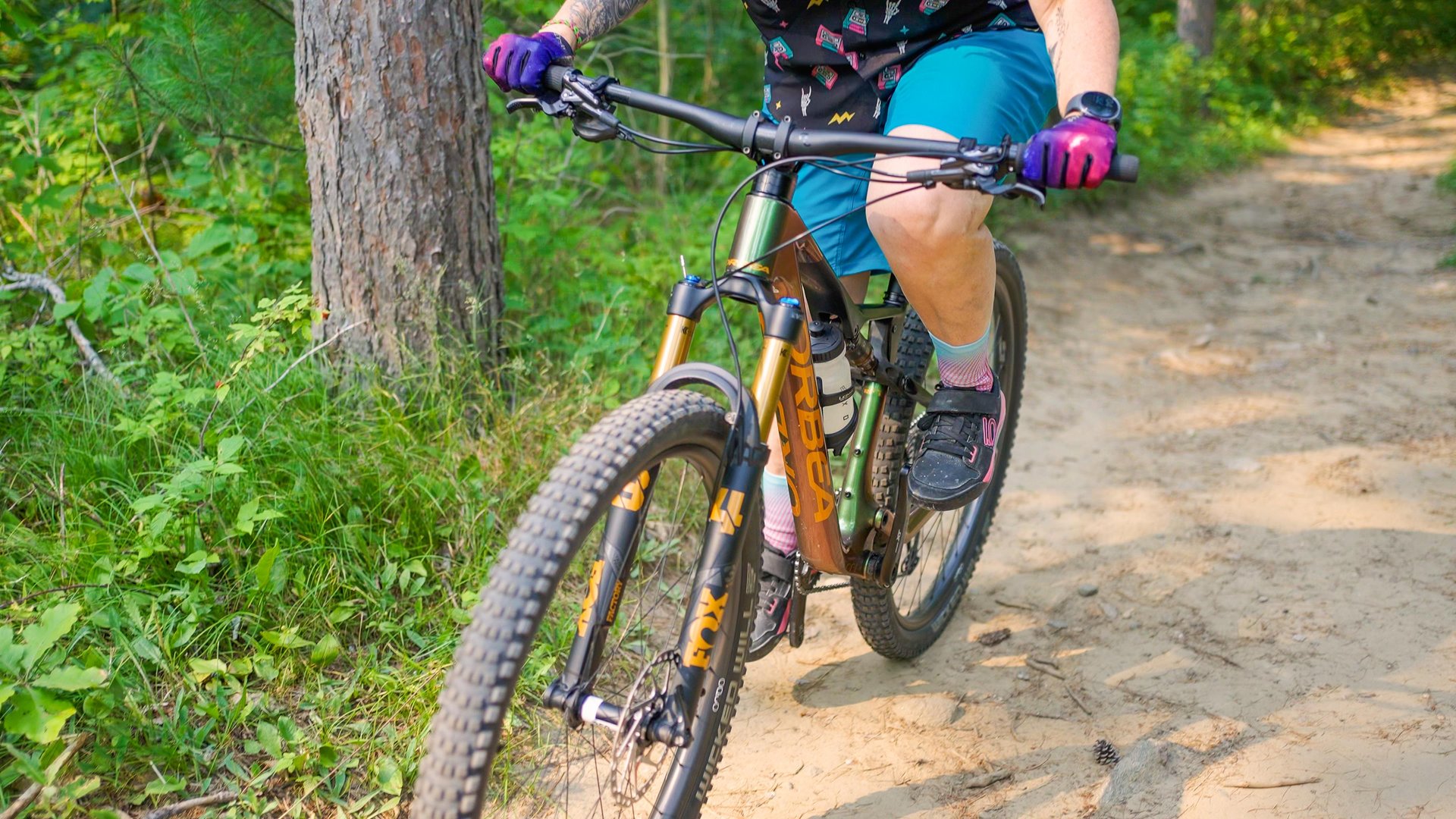 Close up of woman wearing blue shorts while riding a mountain bike on a trail in summer