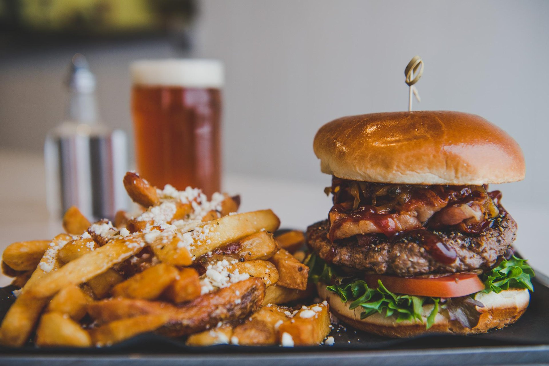 Burger and fries on a plate with a beer in the background