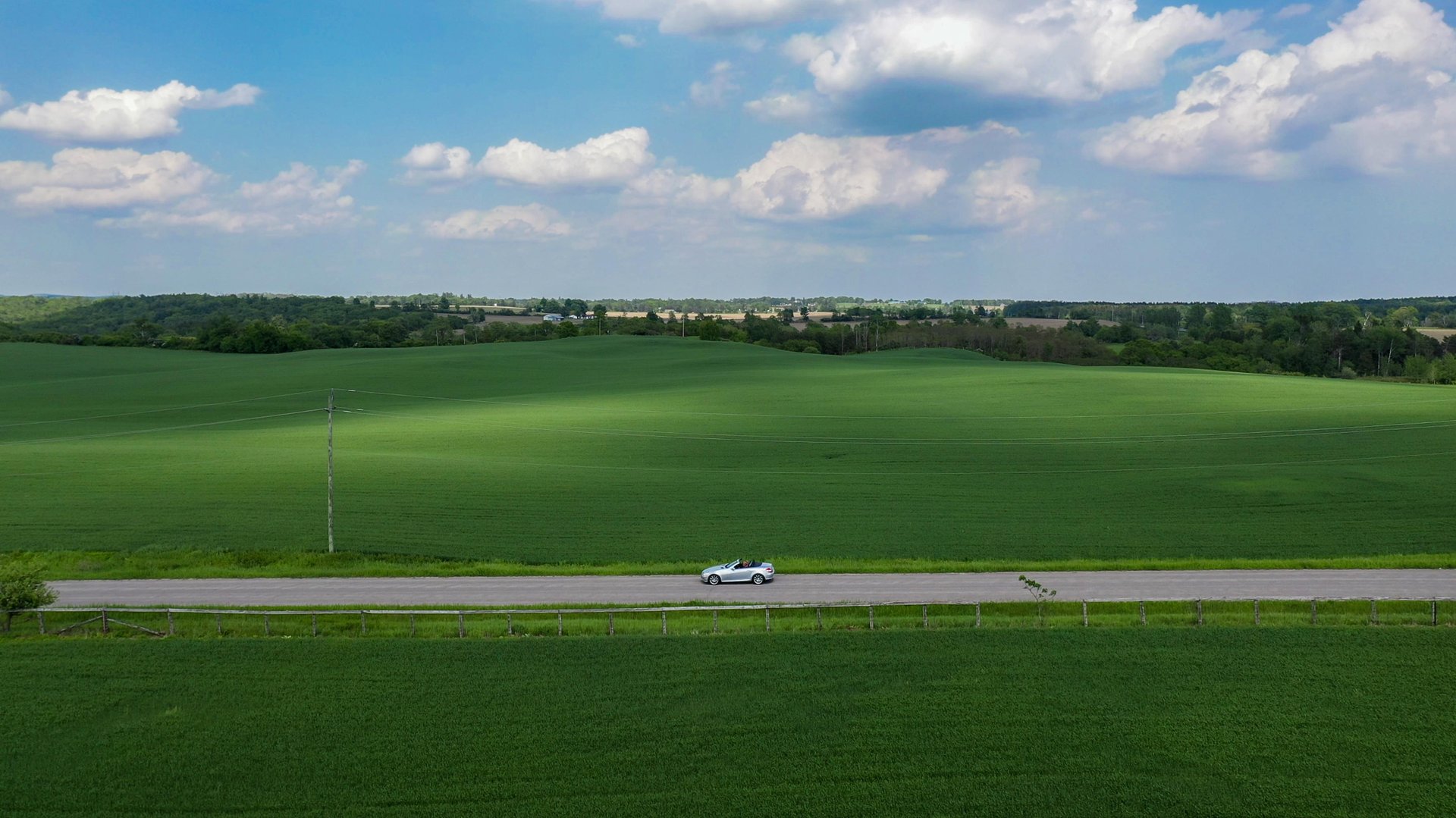 drone view of a car on a country road amid green fields