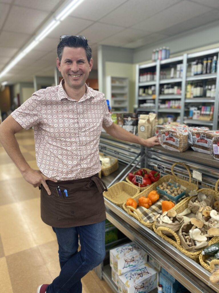Man standing in front of produce at a small market