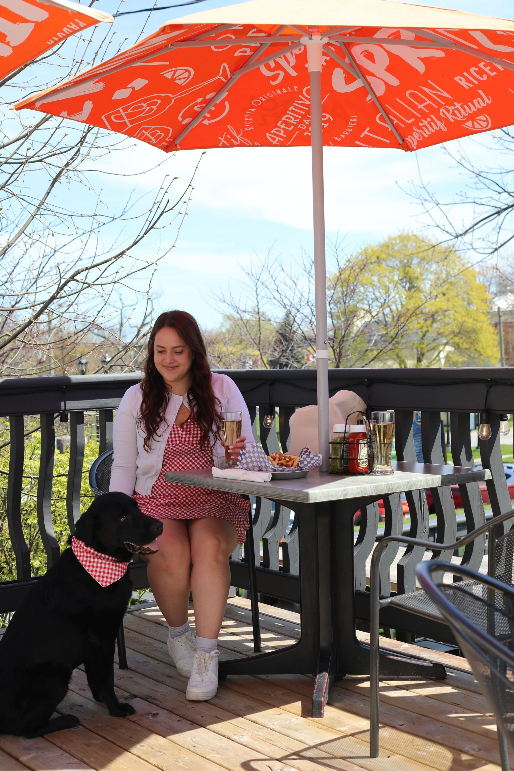 Woman sitting at a restaurant patio table with her black lab