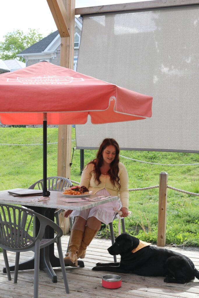 Woman sitting on a patio with her black lab laying down beside her