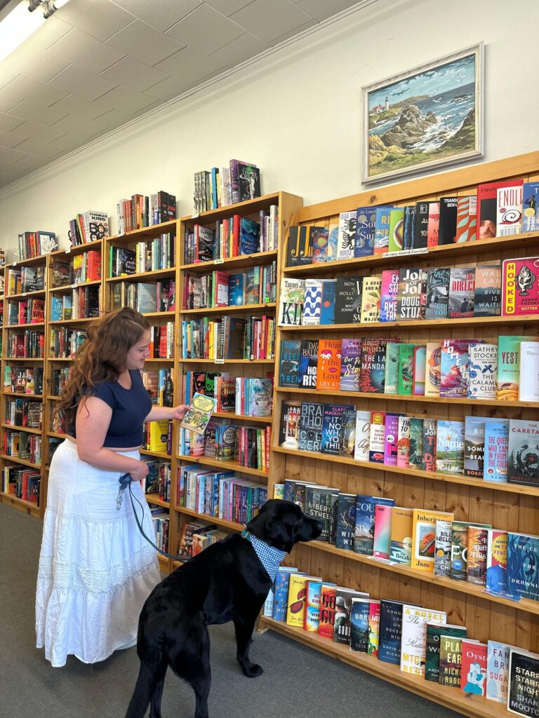 Woman browsing books with her black lab