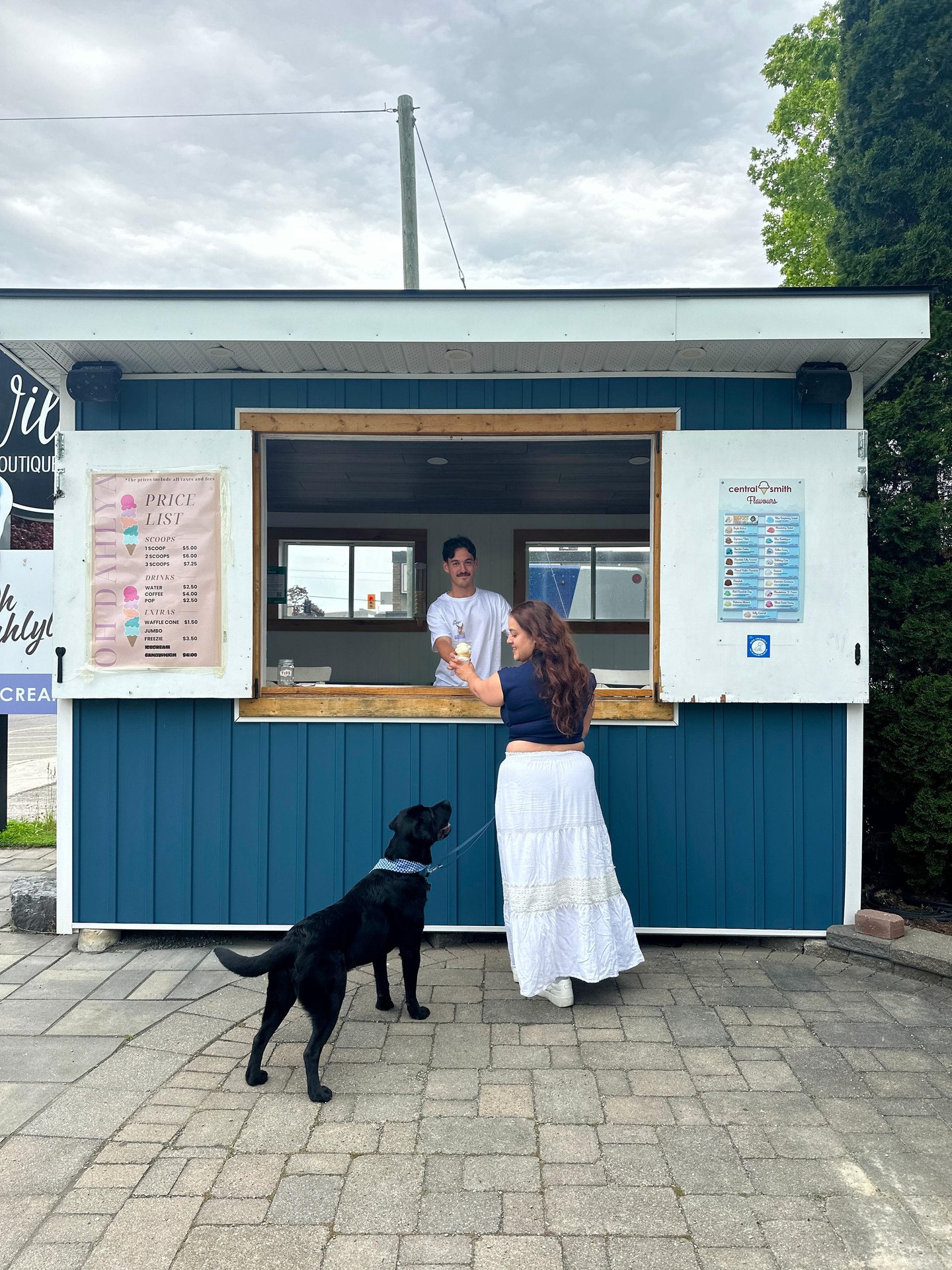 Woman and her black lab ordering ice cream at a small ice cream stand