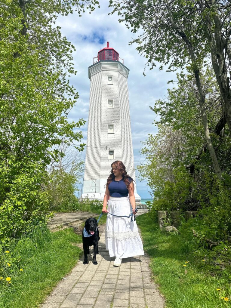 Woman walking her dog in front of a lighthouse at Presqu'ile Provincial Park