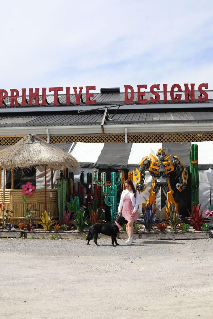 Woman and her black lab standing out front of Primitive Designs