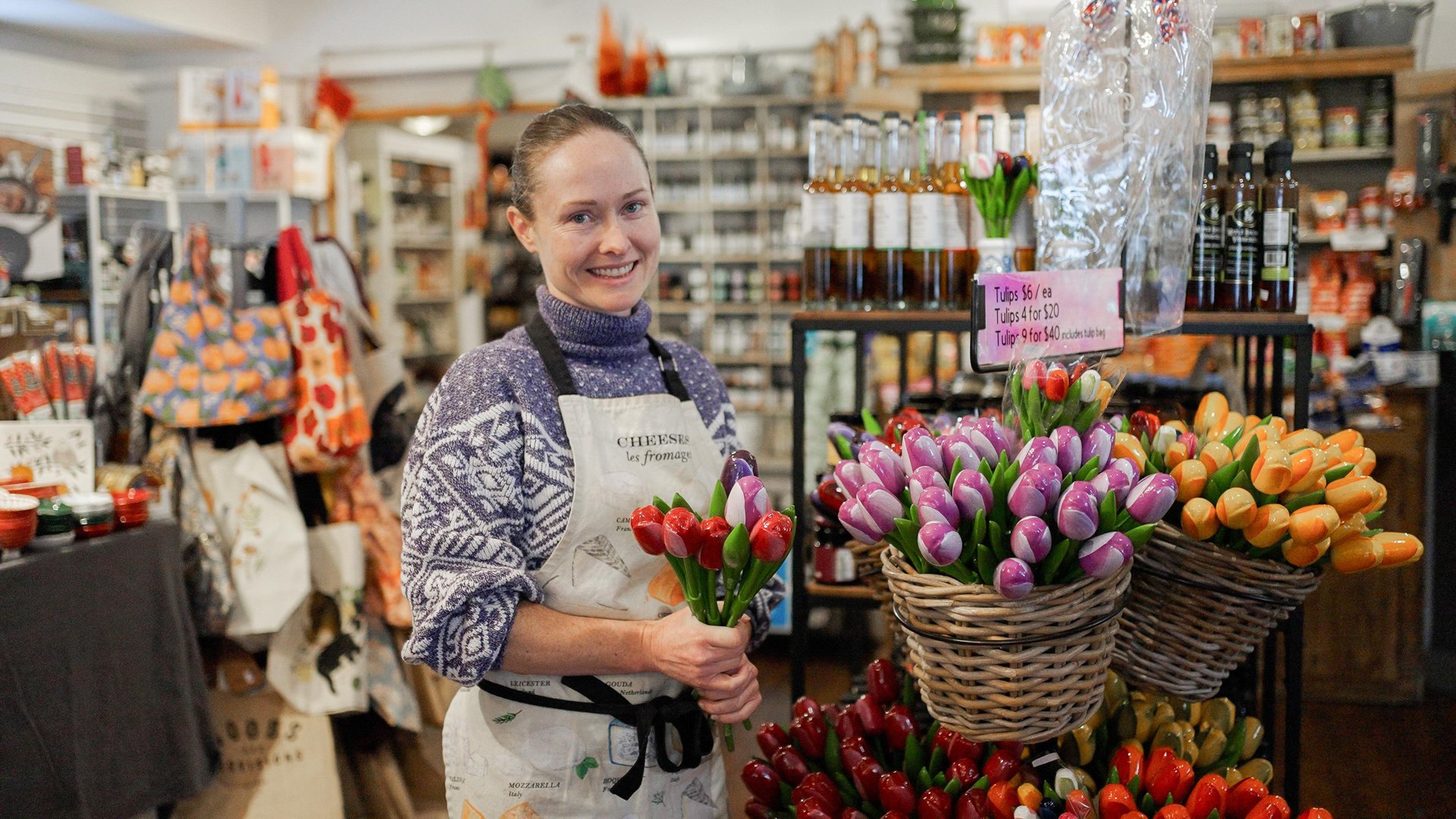 Female shopkeeper holding wooden tulips in a store carrying kitchen items