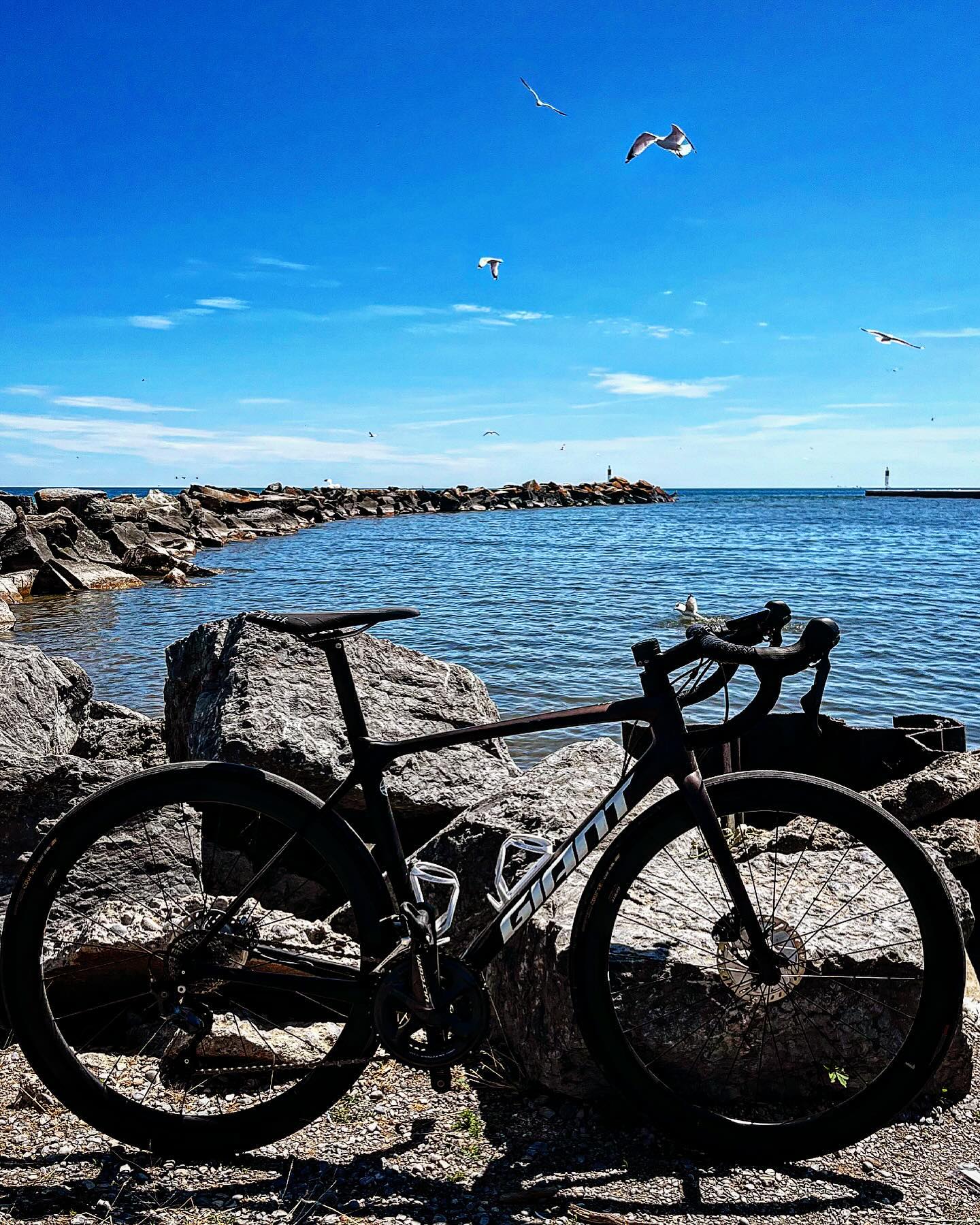 photo by @beers_n_bicycles bike leaning against a rocky breakwater on the shore of Lake Ontario