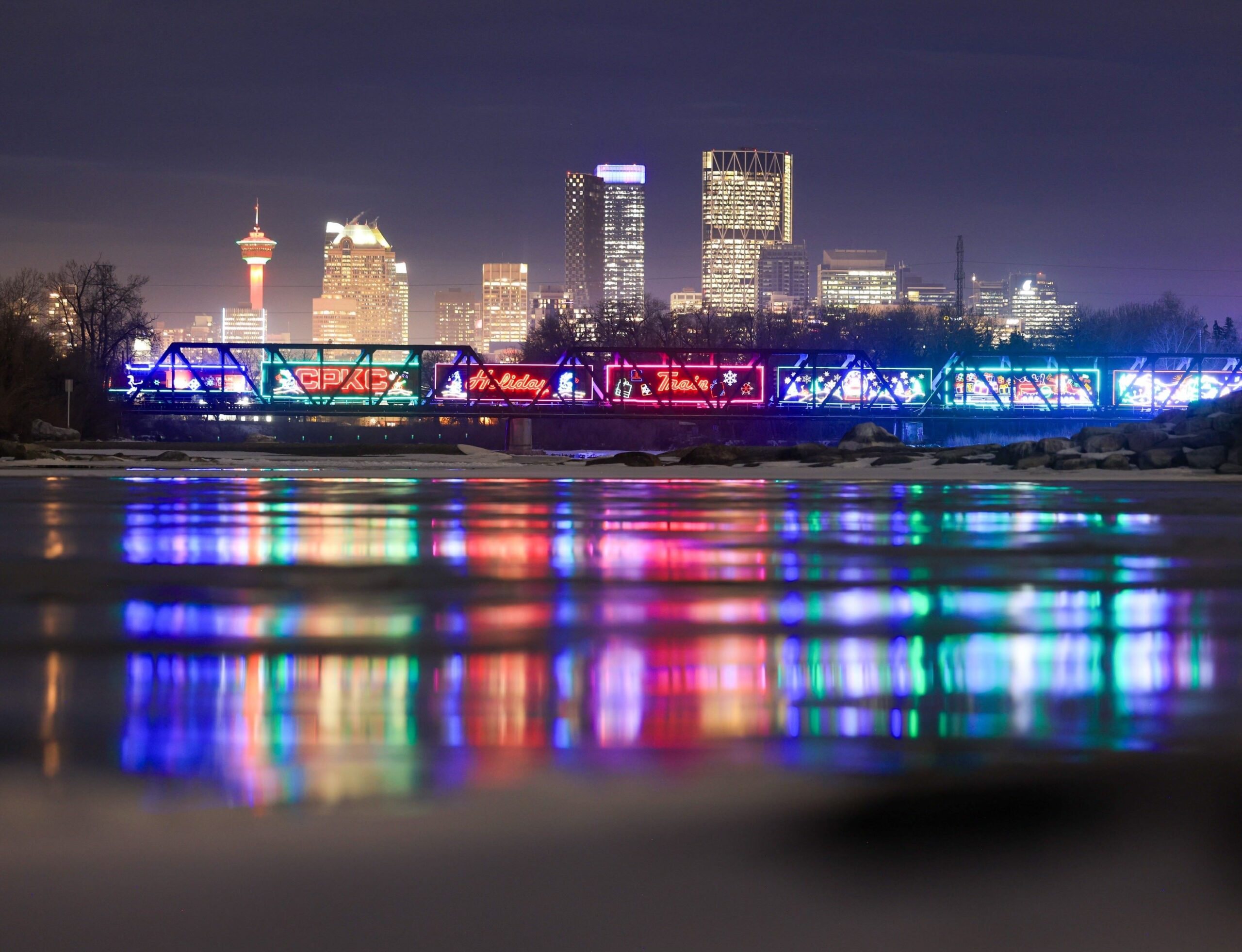 CPKC Holiday Train. Photo of the train lit up, night bridge crossing.