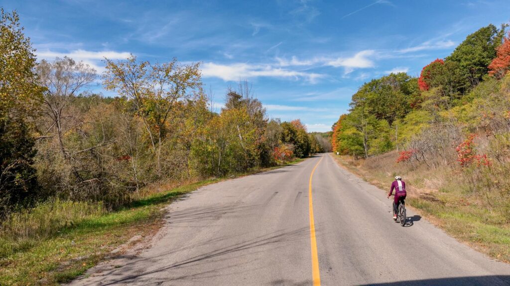 Man riding a bike on a rural road in fall