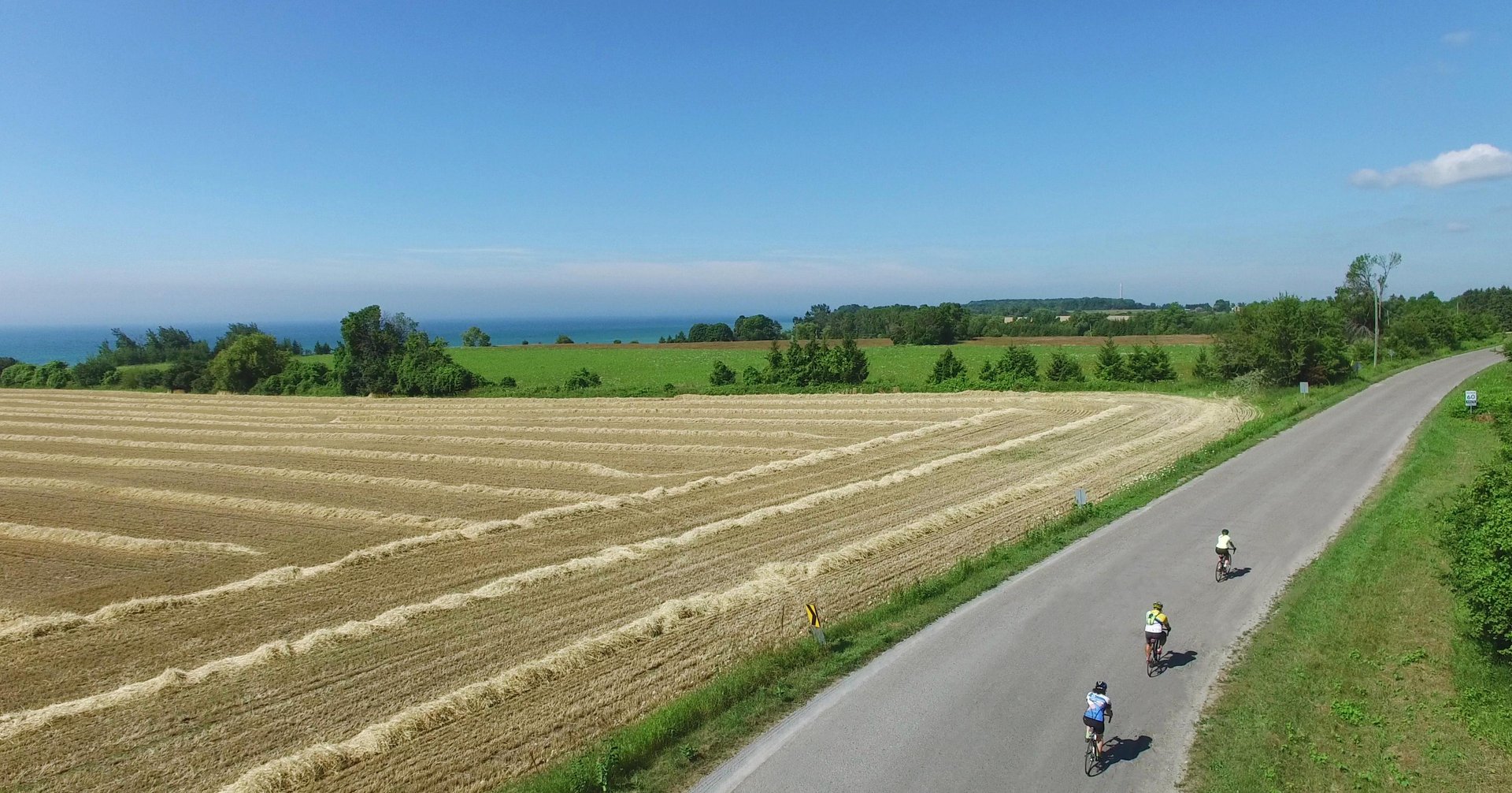 Group of cyclists riding on country road past harvested field